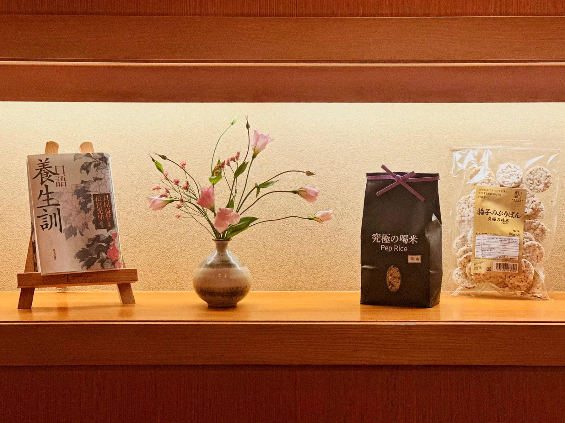店の飾り棚。養生訓の本、季節の花、究極の喝米、駒子のぶりぽん